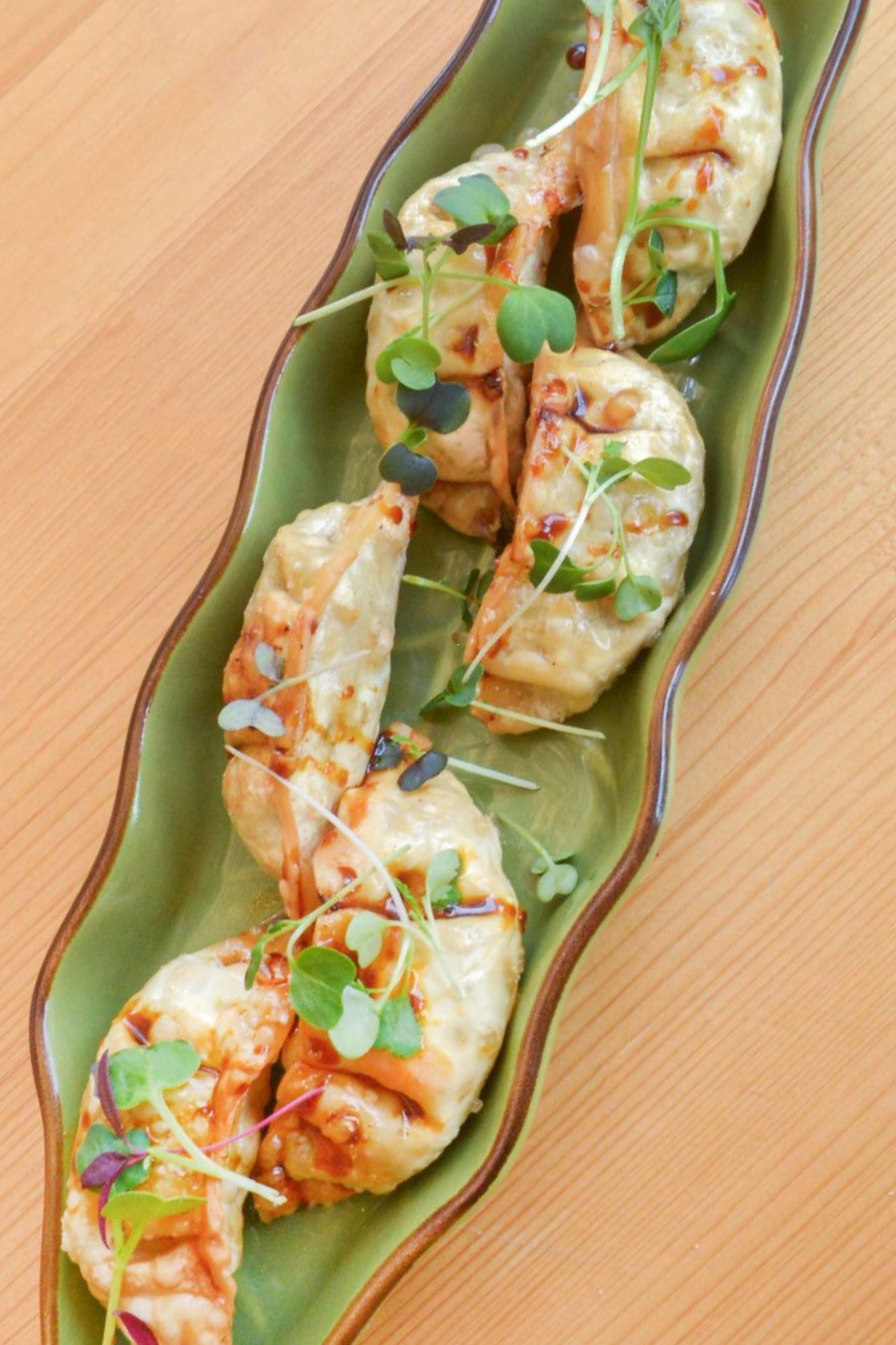 Un plato blanco cubierto con pollo y cebollas verdes sobre una mesa.