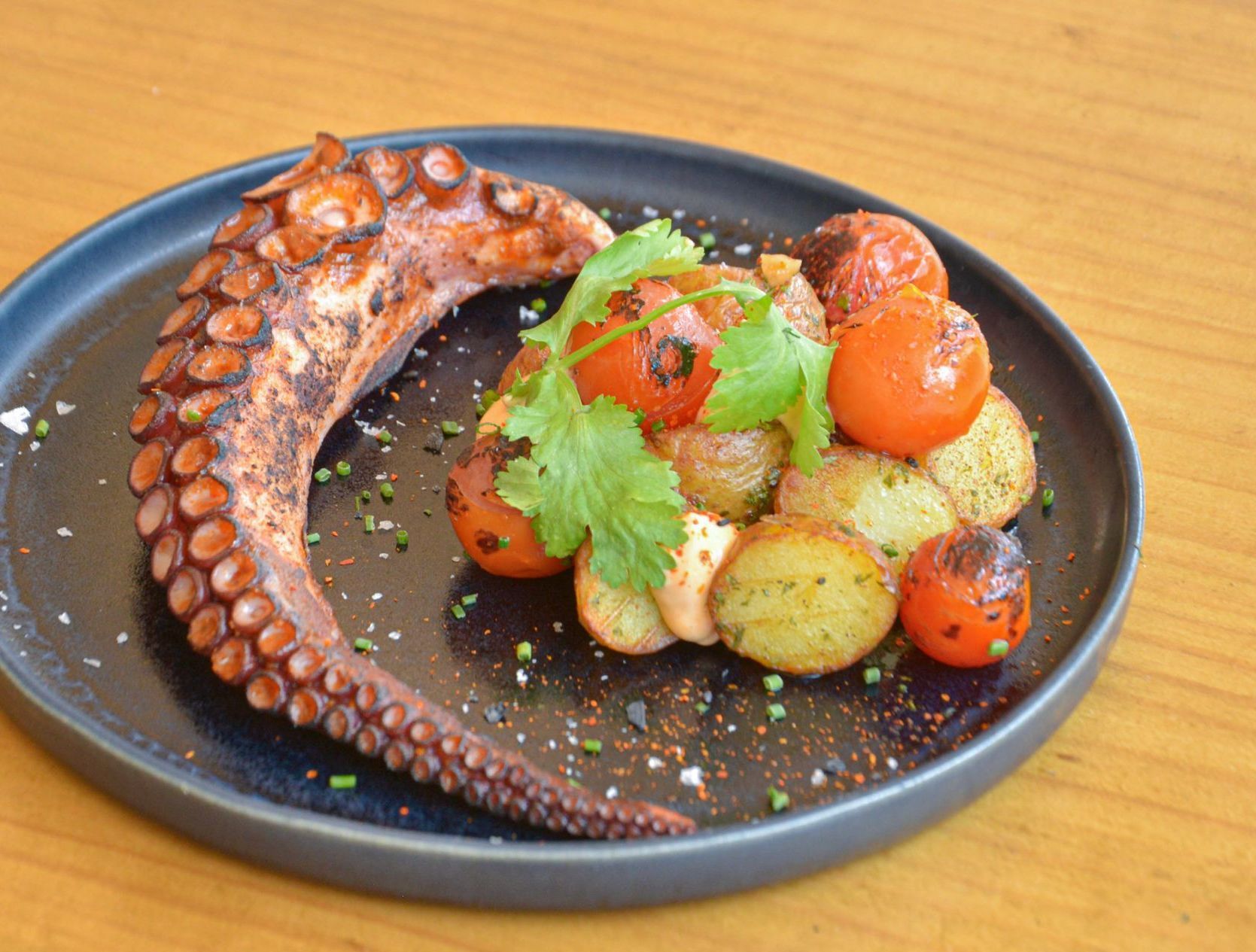 Un plato de comida con un pulpo y patatas encima.