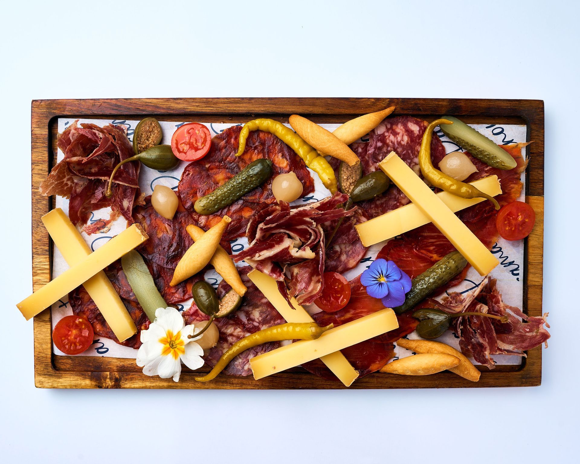 Una bandeja de madera llena de carne y queso sobre una mesa.