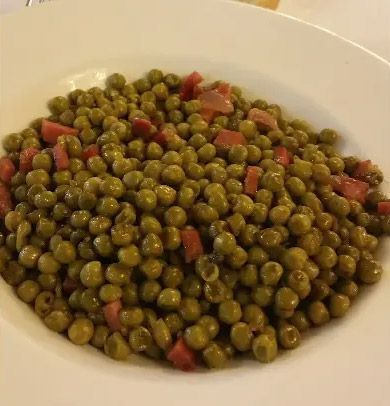Plato de guisantes con dados de jamón rojo.