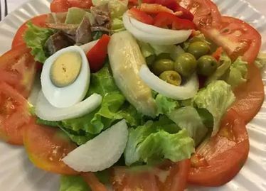 Ensalada con lechuga, tomate, huevo, aceitunas, cebolla y pimiento rojo.