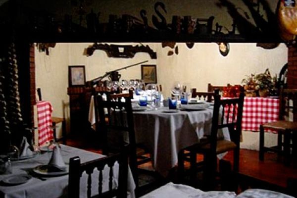 Comedor de restaurante con mesas preparadas para comer, con manteles blancos, sillas y decoración rústica.