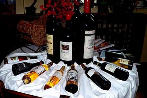 Botellas de vino de diversos tamaños y colores, dispuestas sobre un mantel blanco. Algunas están en posición vertical, otras tumbadas.