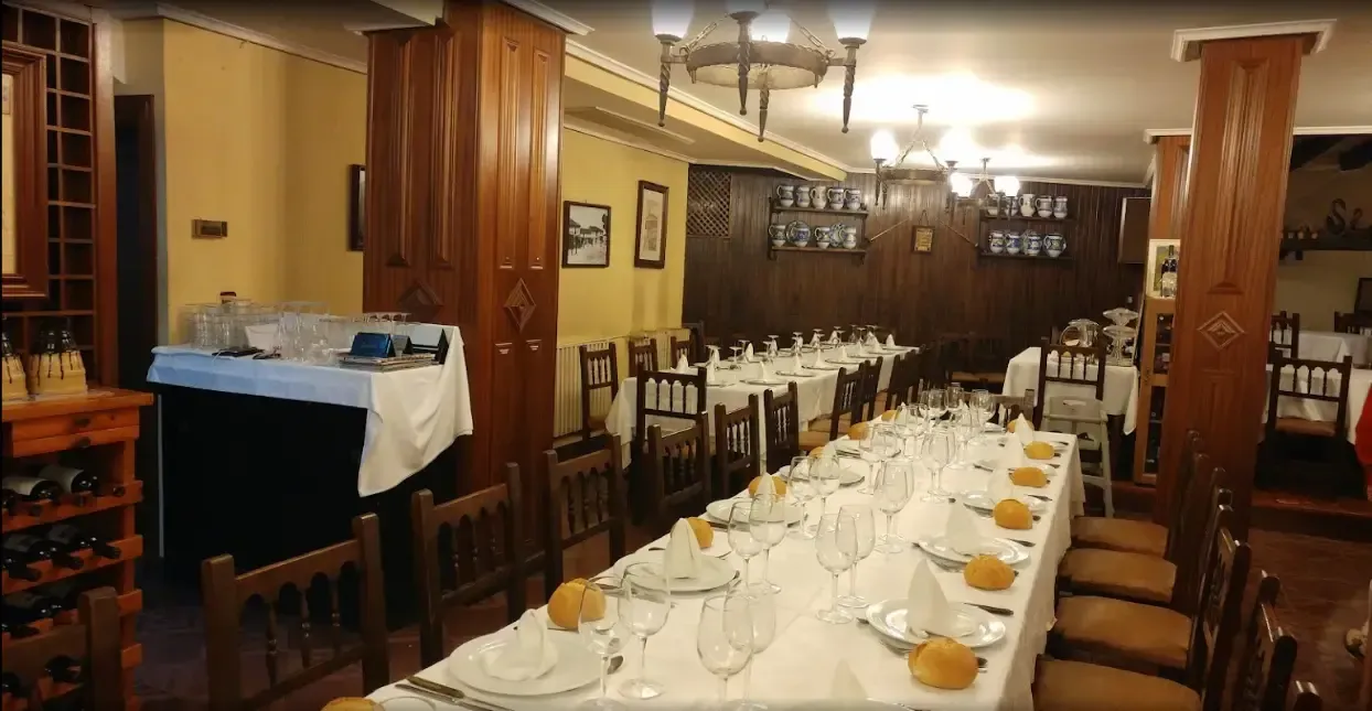Mesas de comedor largas dispuestas para una comida en un restaurante revestido con paneles de madera.