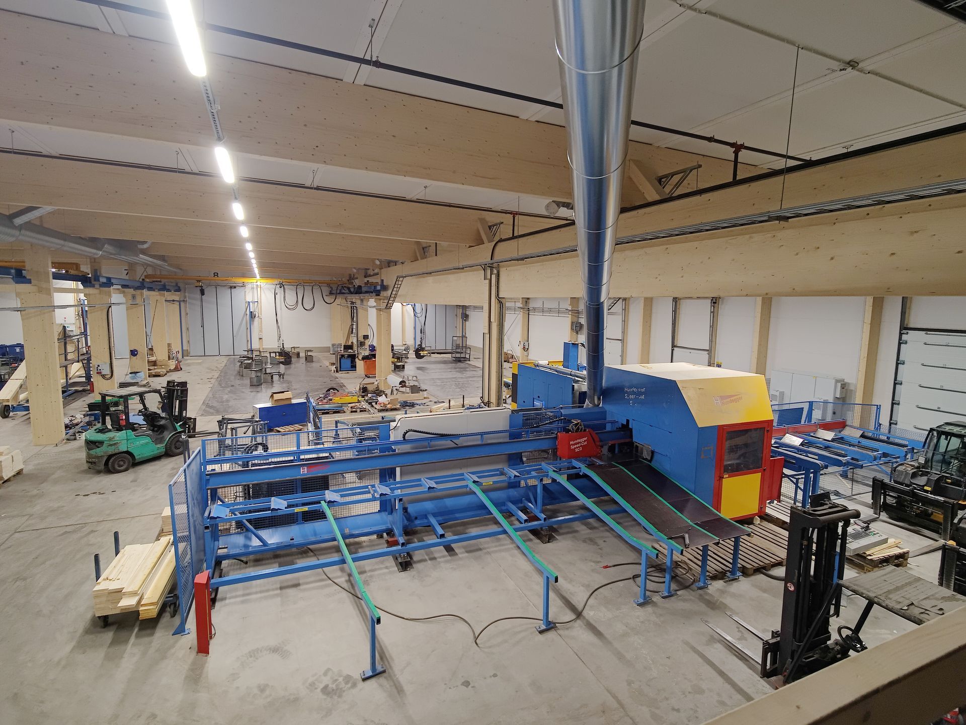 Suuri varasto, jossa on paljon koneita ja vihreä trukki