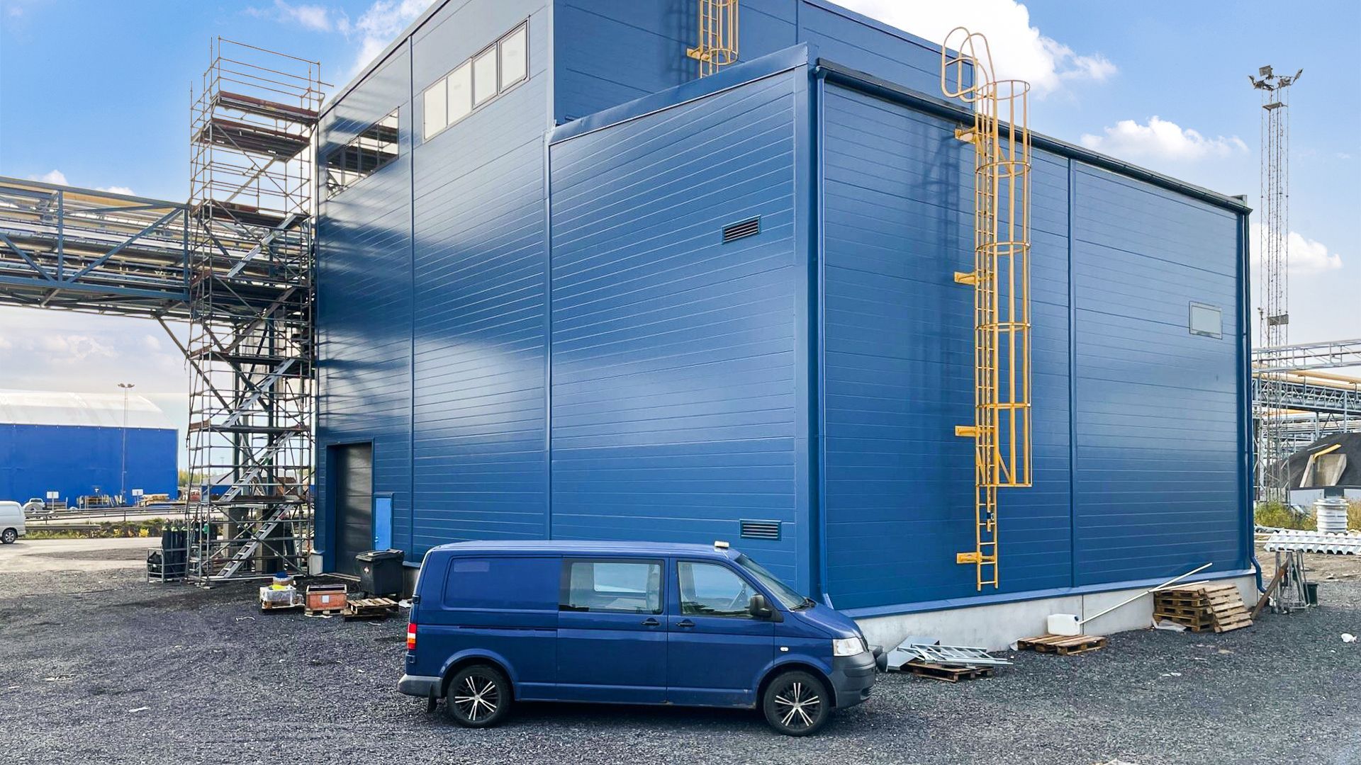 Sininen pakettiauto on pysäköity sinisen rakennuksen eteen