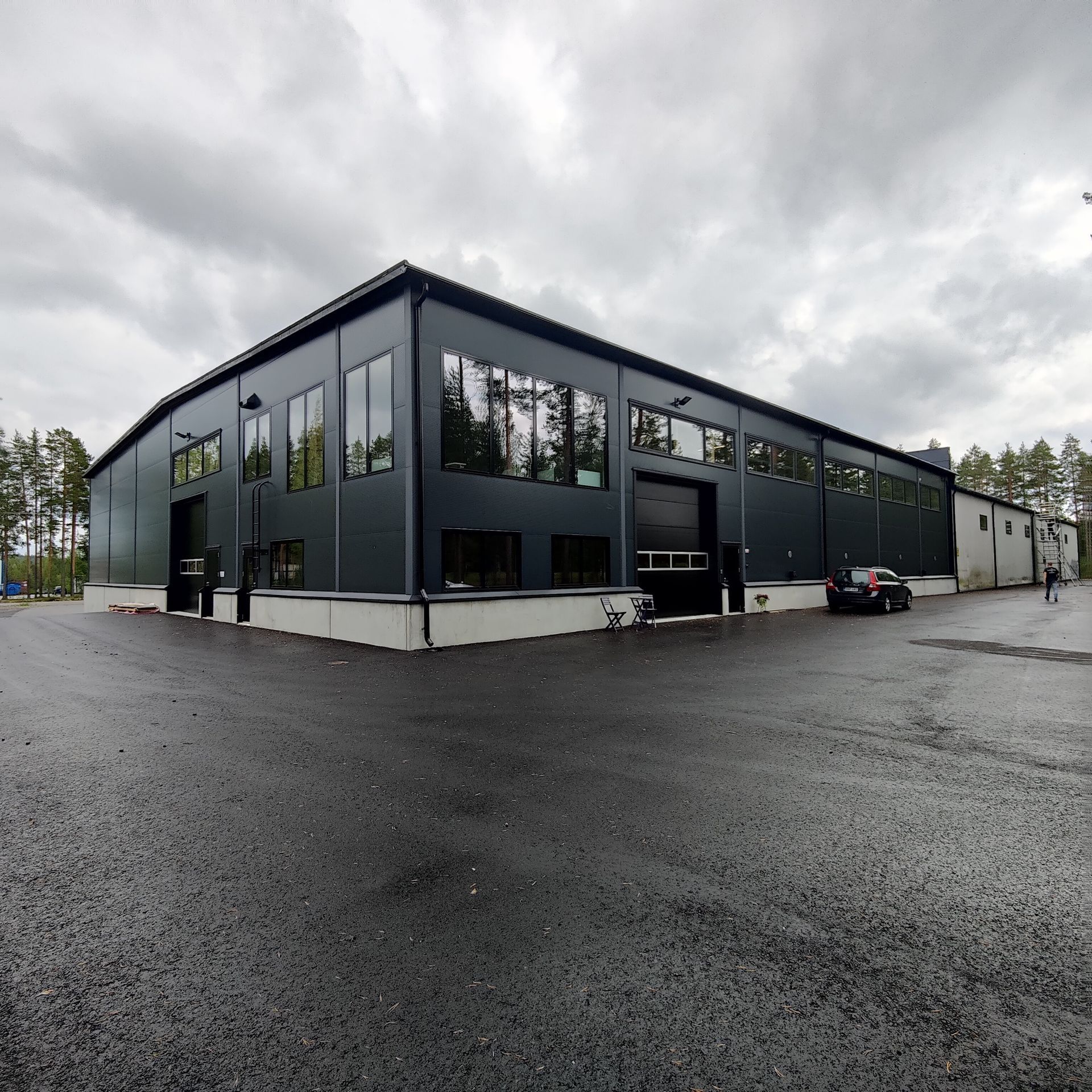 Suuri rakennus, jossa on paljon ikkunoita ja jonka edessä on pysäköity auto