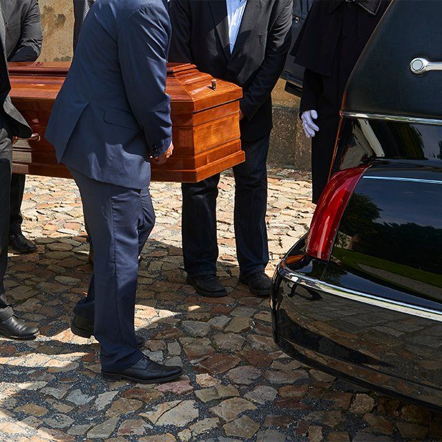 Services de pompes funèbres transportant le cercueil du défunt jusqu'au corbillant