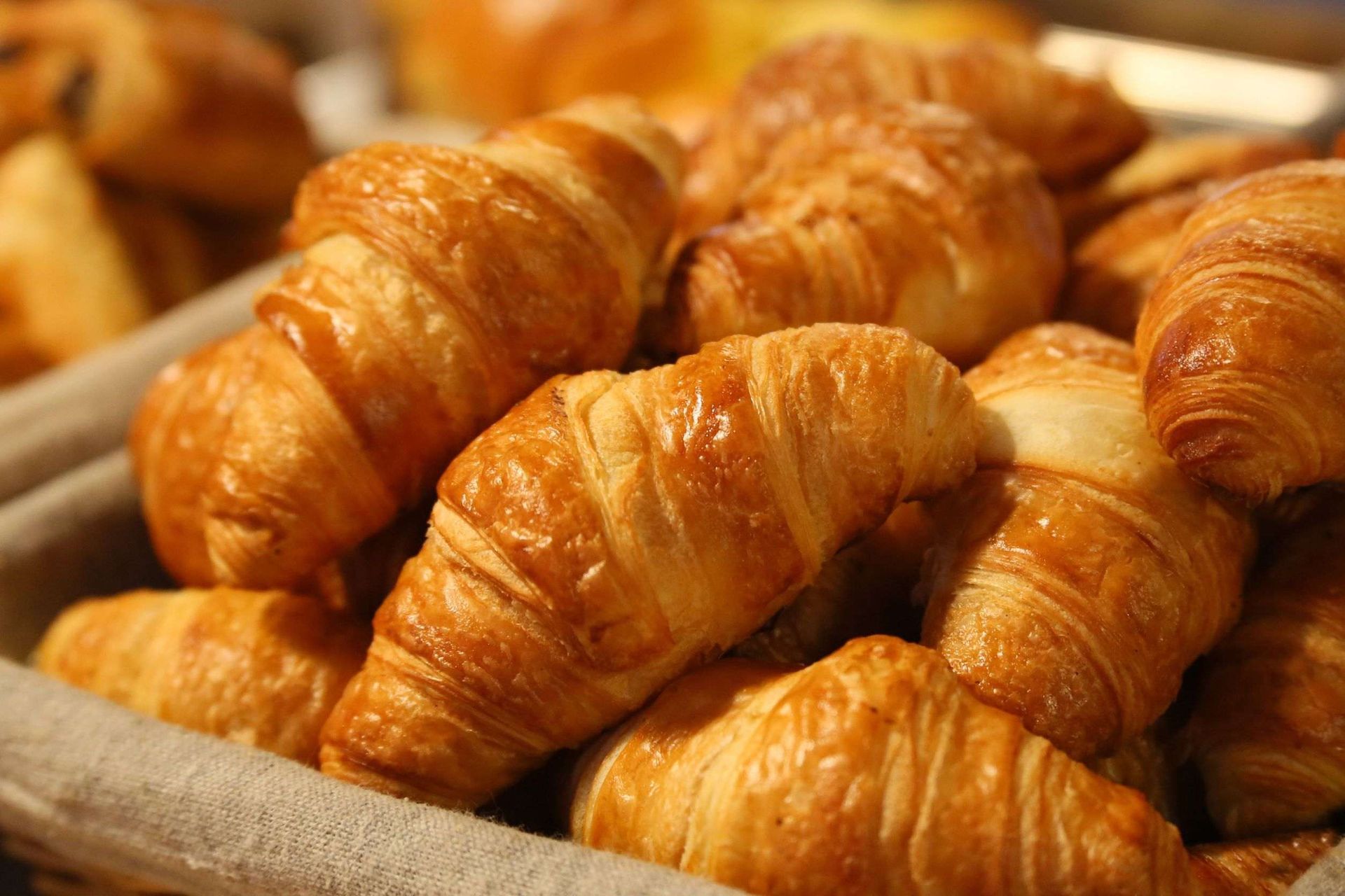 Una cesta llena de croissants está sobre una mesa.