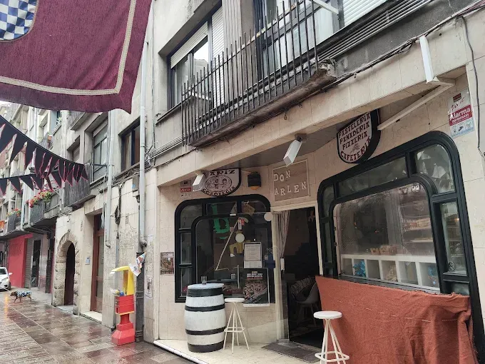 Un edificio con un balcón y barriles delante.