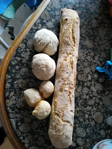 Una hogaza de pan y tres bolas de masa están sobre una mesa.