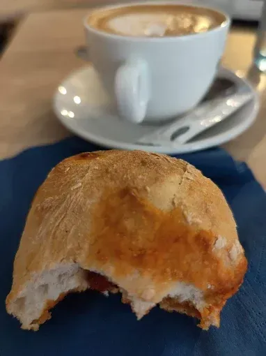 Un primer plano de un trozo de pan en una servilleta junto a una taza de café.