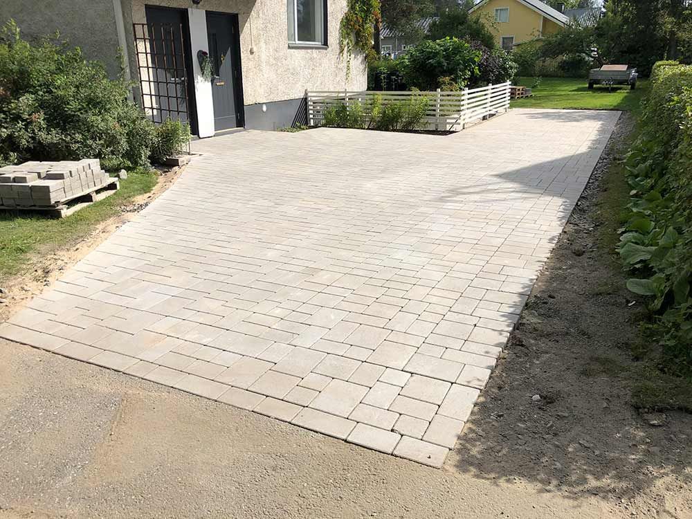 Vaaleanharmailla suorakaiteen muotoisilla paloilla päällystetty ajotie talolle johtaa.