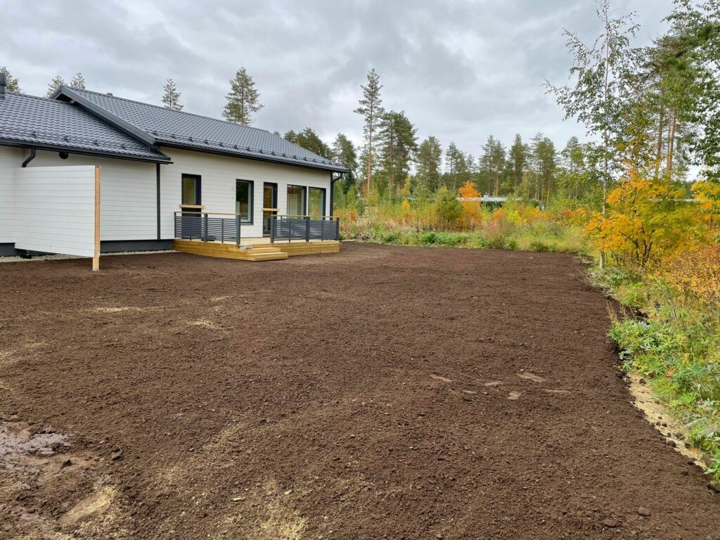 Talo, jossa on vastaleikattu nurmikko, puiden ympäröimänä. Pilvinen taivas.