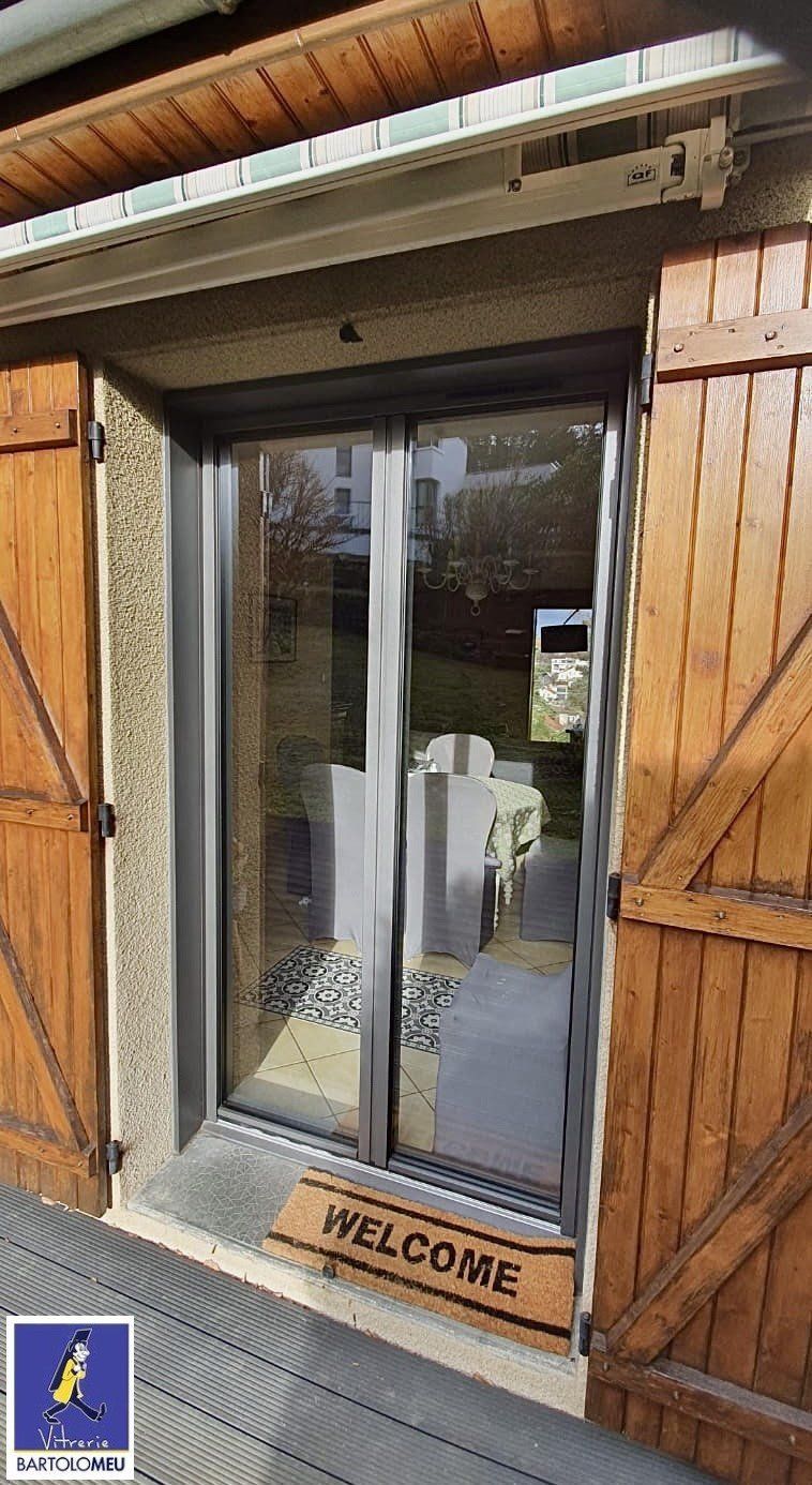 Porte-fenêtre grise vue de l'extérieur avec volets en bois