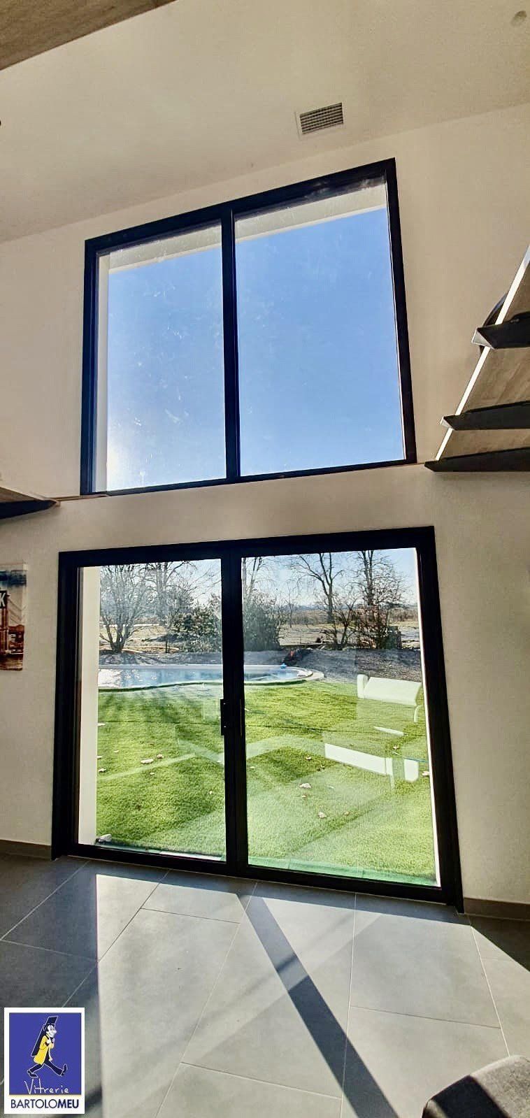 Baie vitrée coulissante surmontée d'une grande baie vitrée