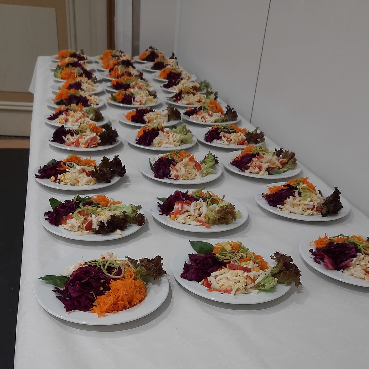 eine Reihe von Tellern mit verschiedenen Salatsorten auf einem Tisch