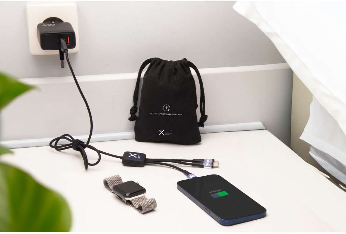 Téléphone branché qui chargé à côté d'une montre et d'un sac