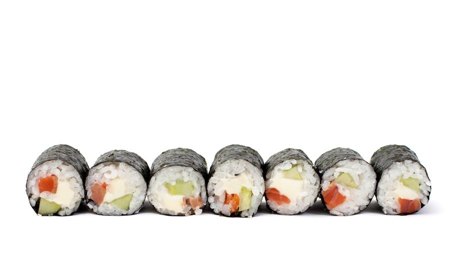 Una fila de rollos de sushi con verduras sobre un fondo blanco.