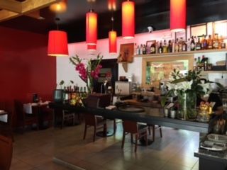 Un restaurante con barra, mesas y sillas.