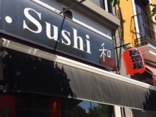 Un restaurante llamado sushi está ubicado al costado de un edificio.