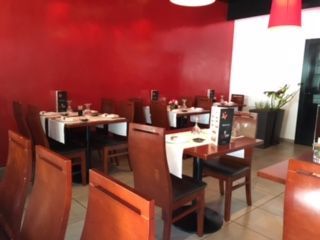 Un restaurante con mesas y sillas y una pared roja.