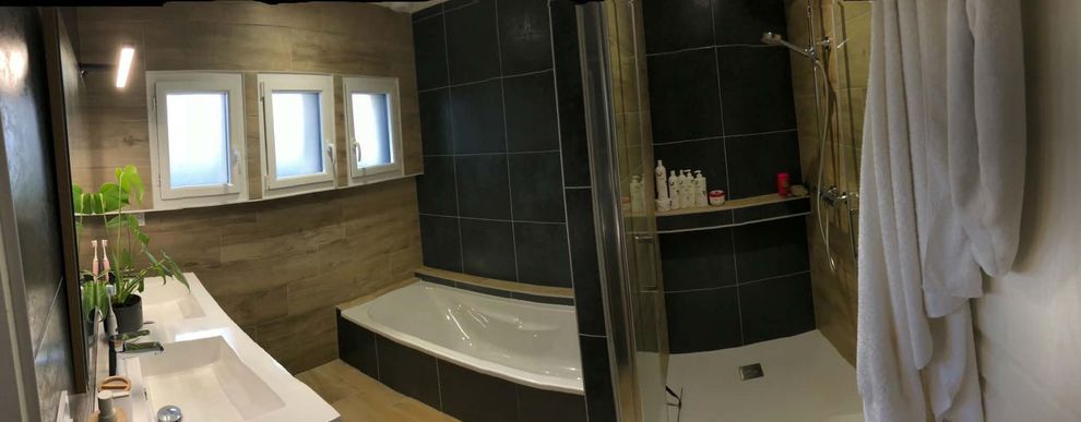Salle de bains moderne avec baignoire îlot, double vasque, douche carrelée et serviettes.