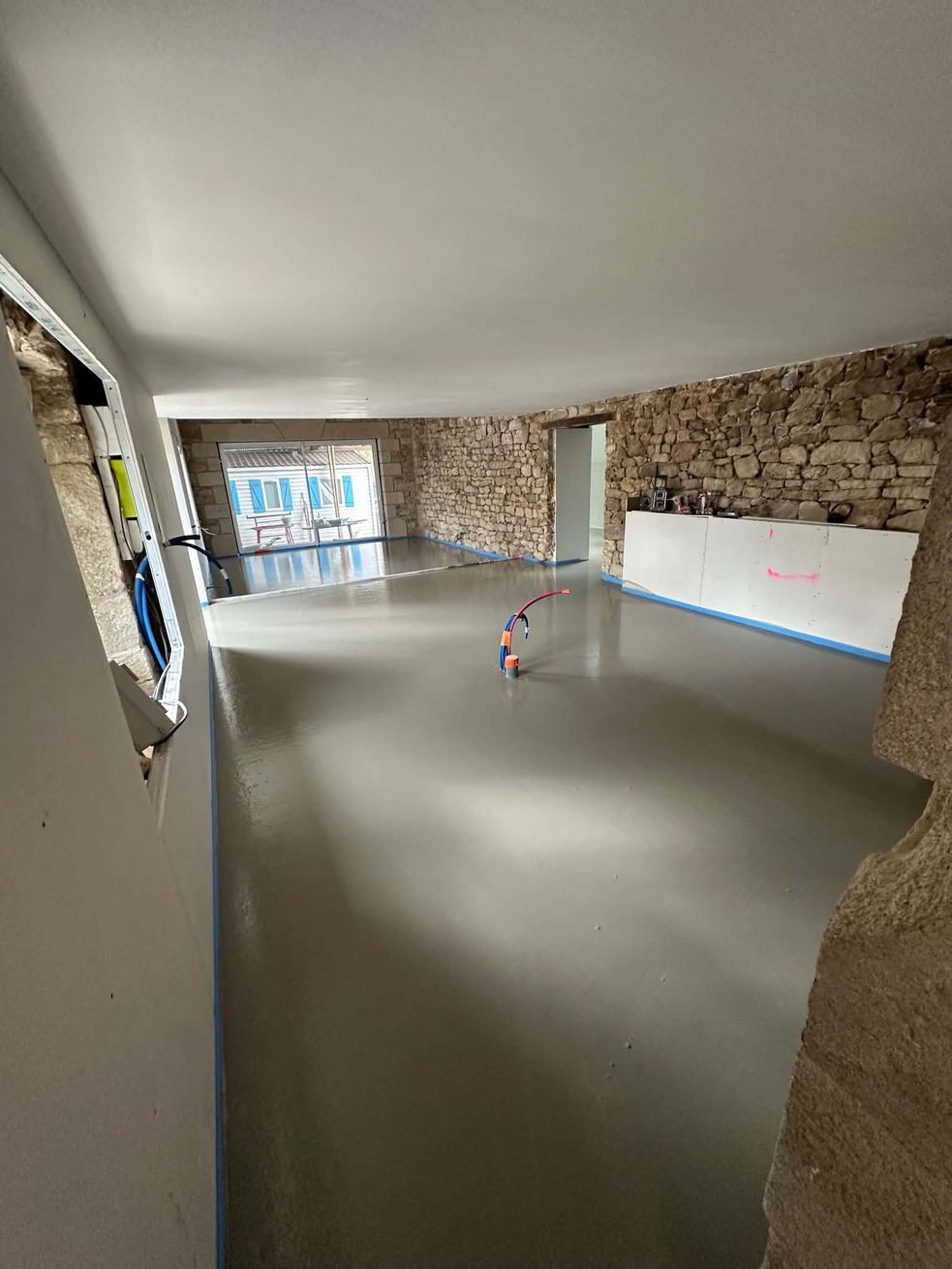 Pièce intérieure vide avec des murs, un sol lisse et un tableau le long du mur de droite.