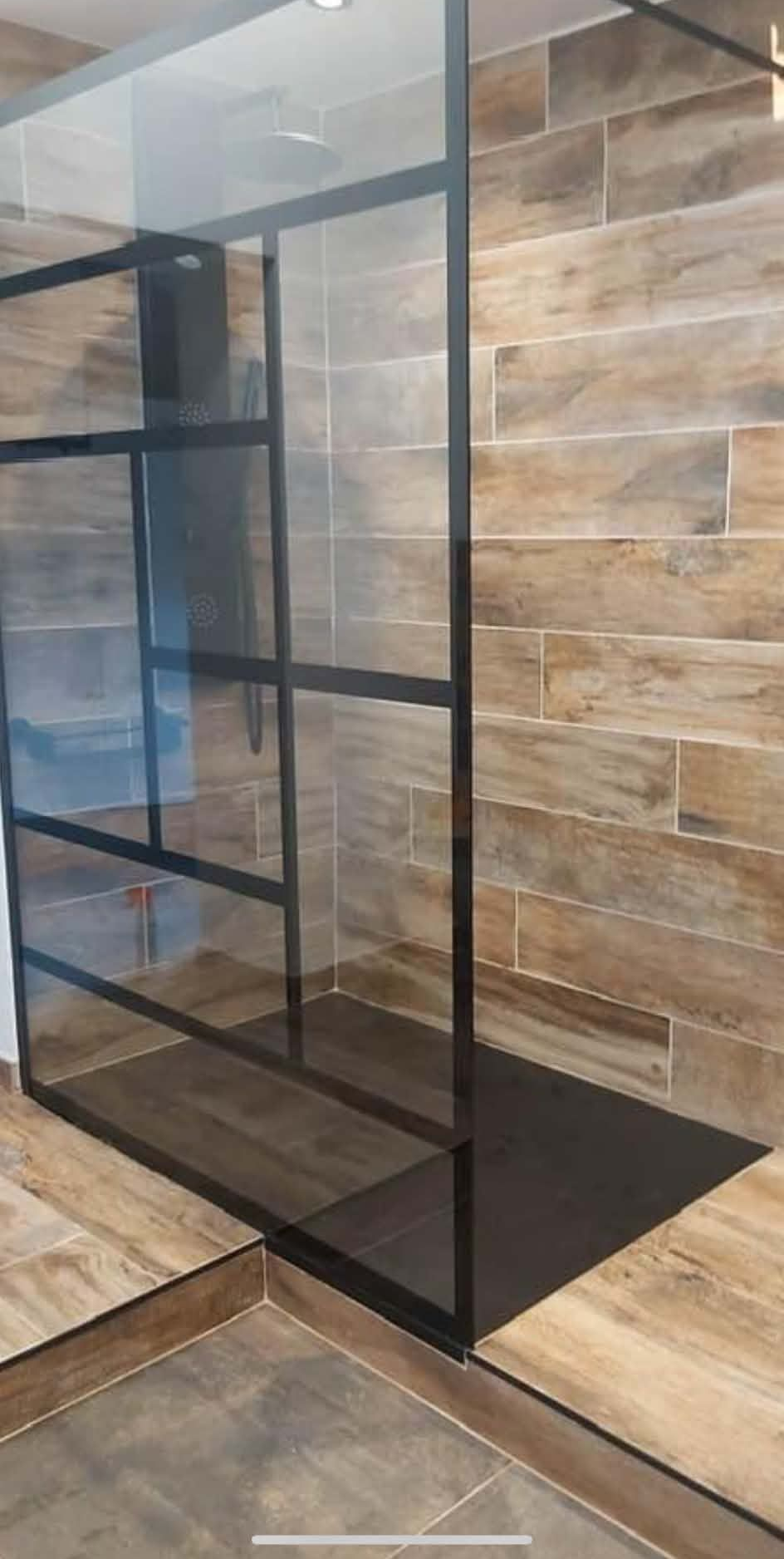 Étagère en verre à cadre à côté d'un mur en carrelage de pierre et d'un sol carrelé dans une pièce moderne.