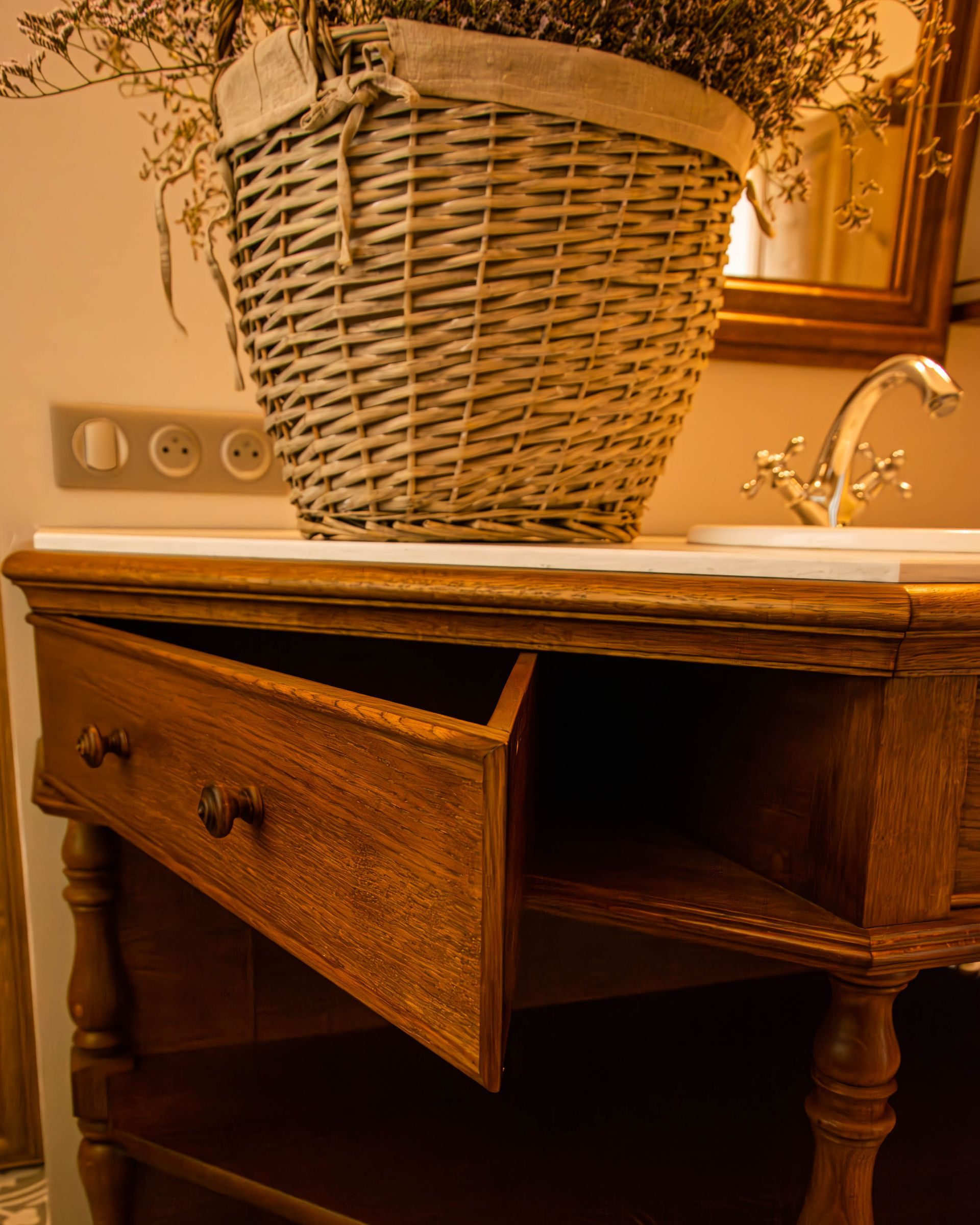 Salle de bains rustique avec tiroir en bois ouvert et panier en osier, créée par Arole, menuiserie à Nîmes.