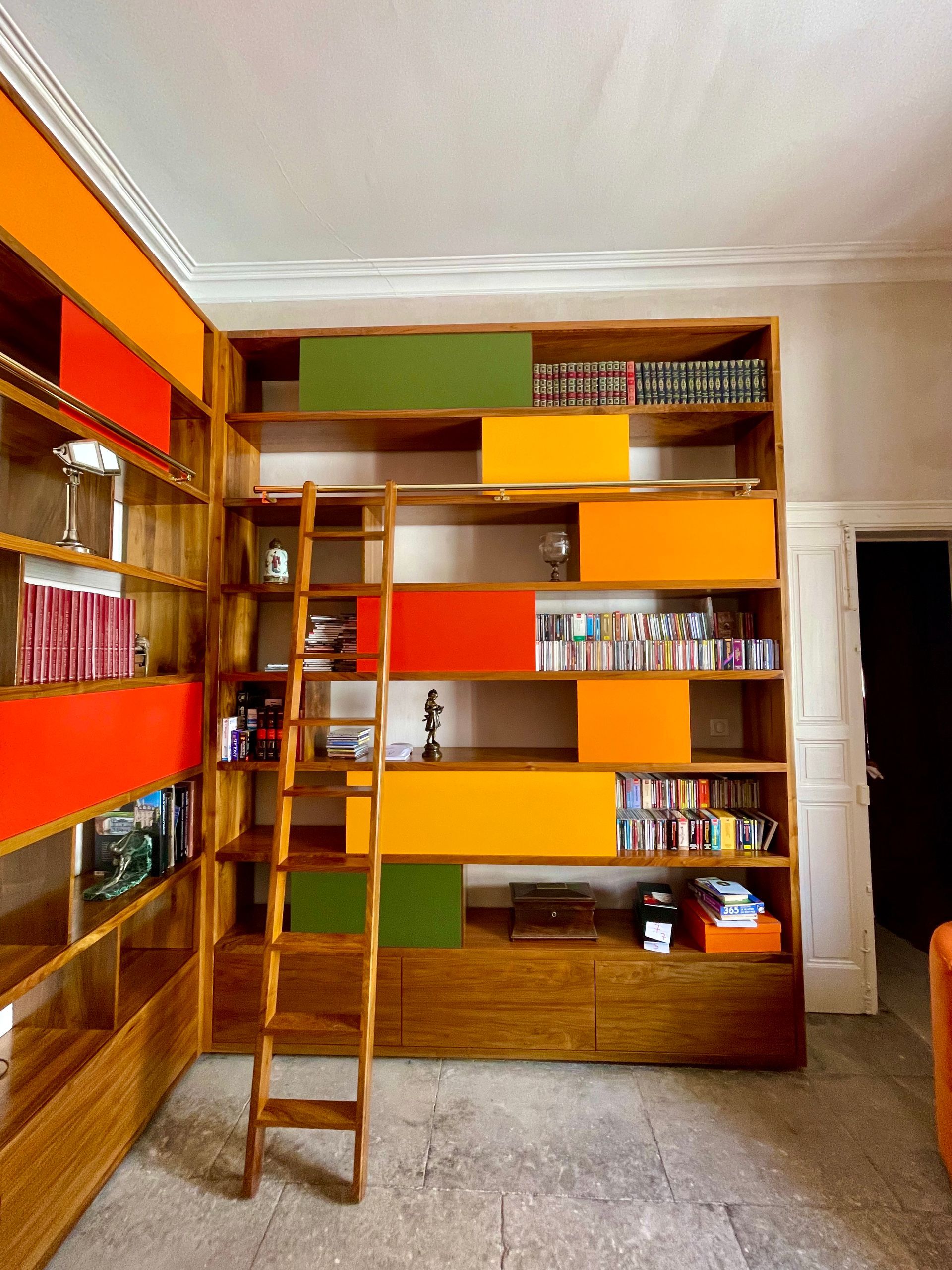 Bibliothèque en bois personnalisée avec des couleurs et une échelle par Arole, spécialiste de la menuiserie à Nîmes.