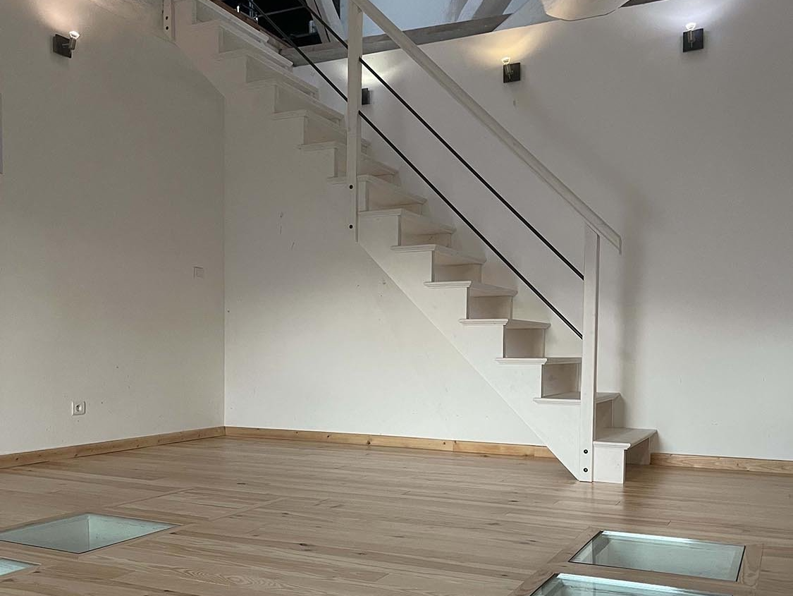 Escalier en bois blanc dans une pièce avec des fenêtres au sol