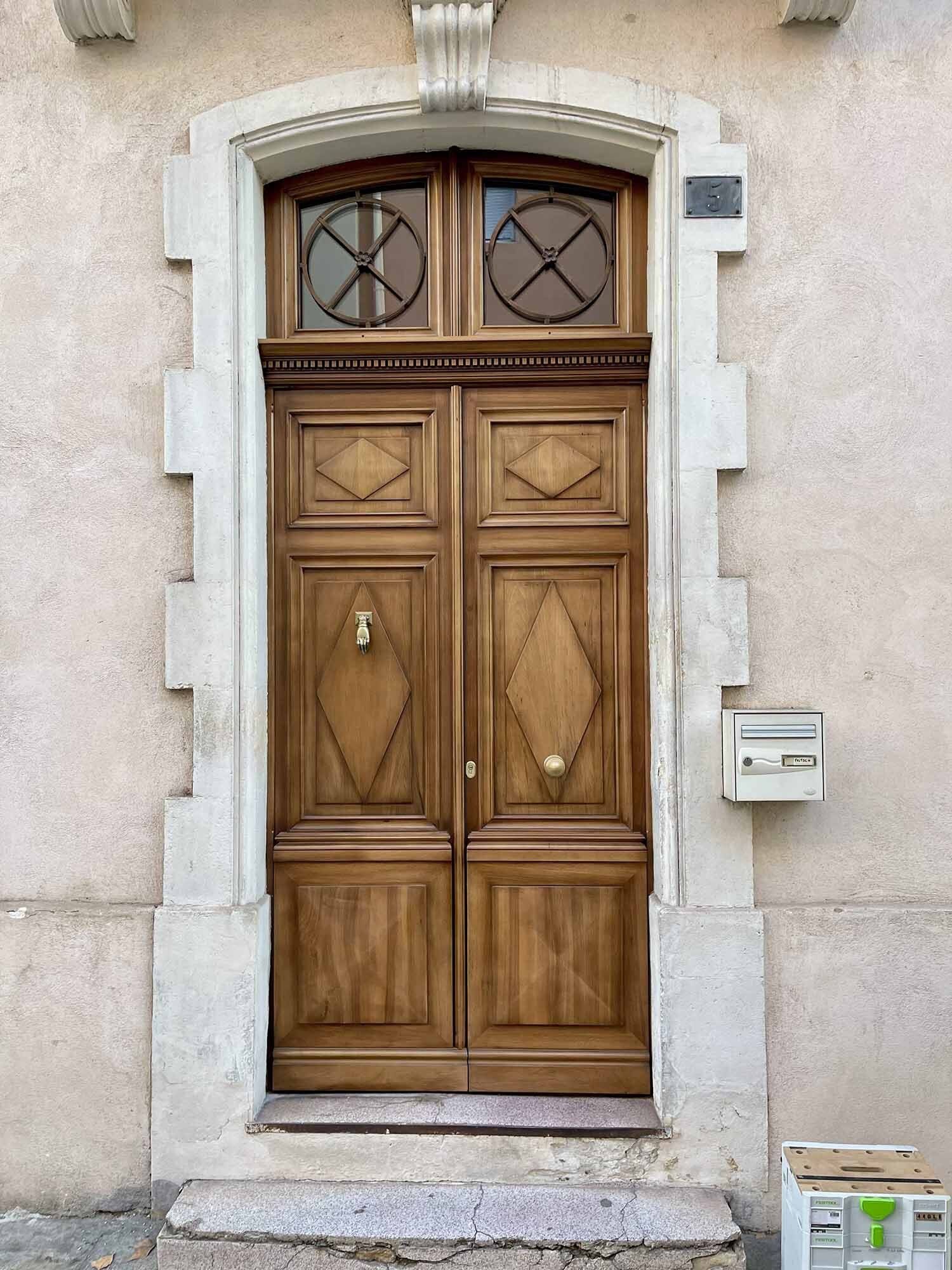 Porte d'entrée en bois massif avec encadrement en pierre, réalisée par Arole, Nîmes