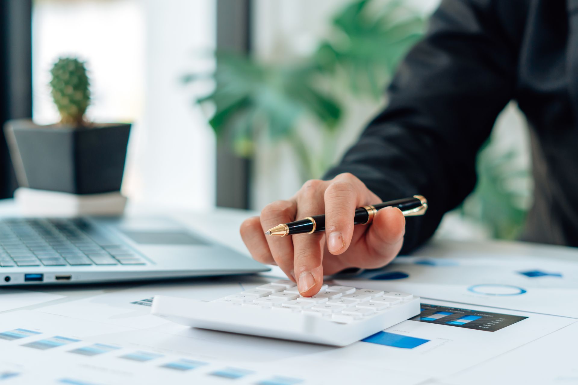 Une personne utilise une calculatrice à côté d'un ordinateur portable sur un bureau dans un bureau.