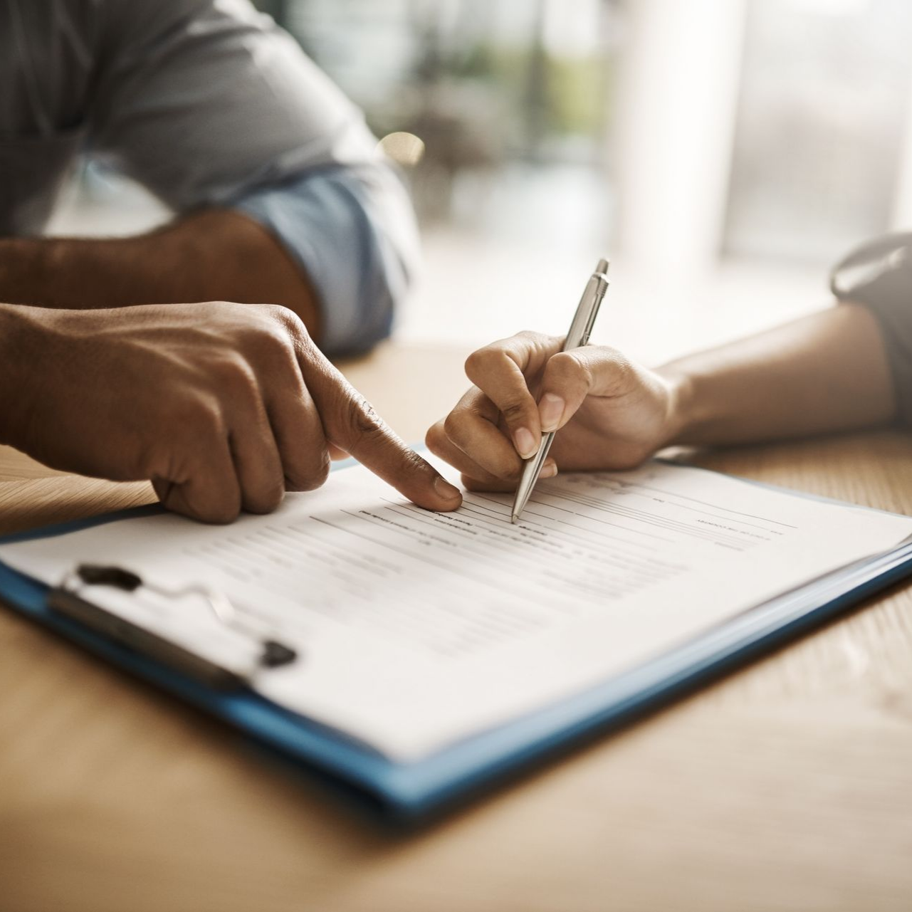 Deux personnes consultent un document et pointent du doigt un graphique sur un bloc-notes à une table.