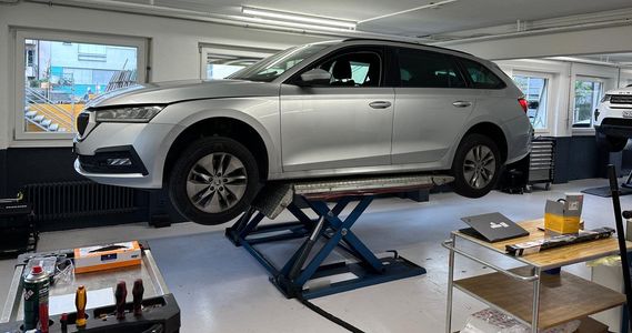 Person prüft Motoröl mit Ölmessstab. Motorraum eines schwarzen Autos, grüner Hintergrund.