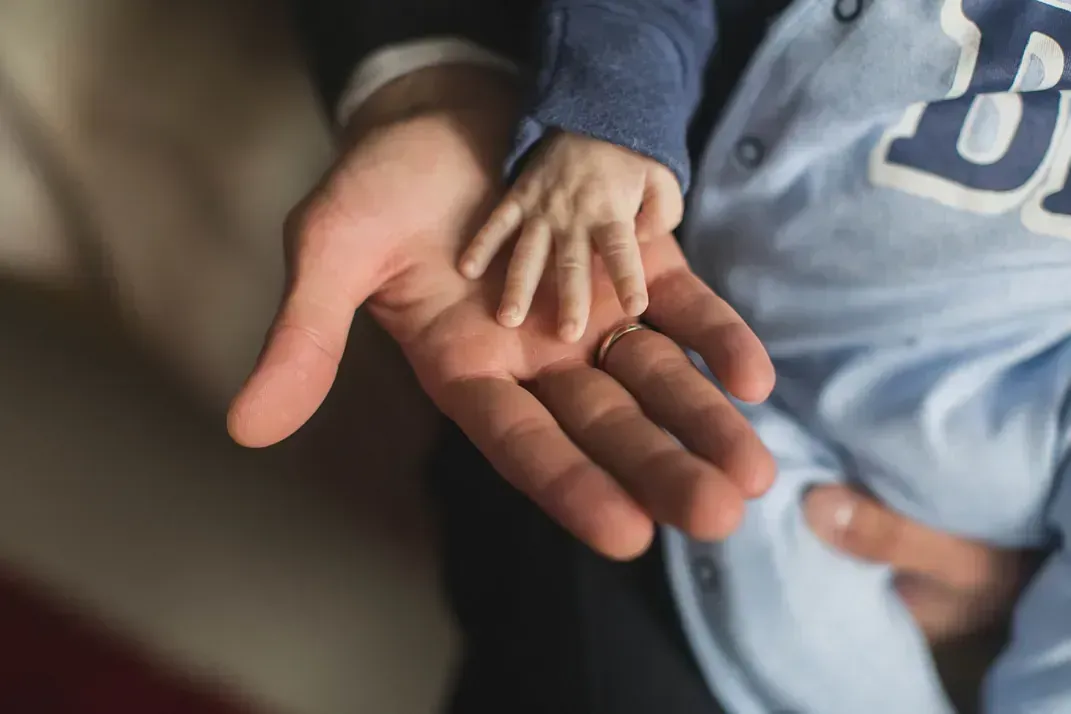 Un hombre sostiene la mano de un bebé en la palma de su mano.
