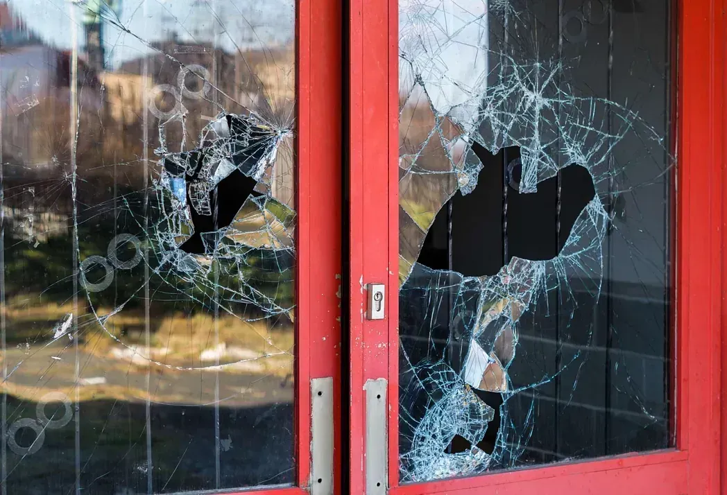 Una puerta roja con una ventana de vidrio rota.