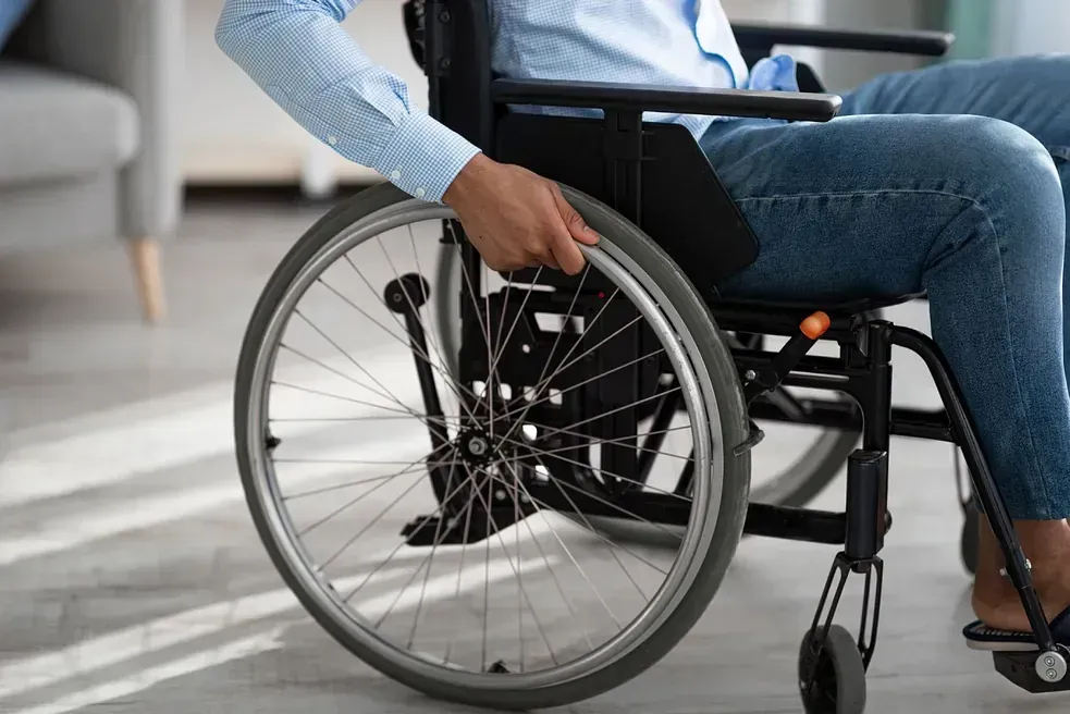 Un hombre está sentado en una silla de ruedas en una sala de estar.