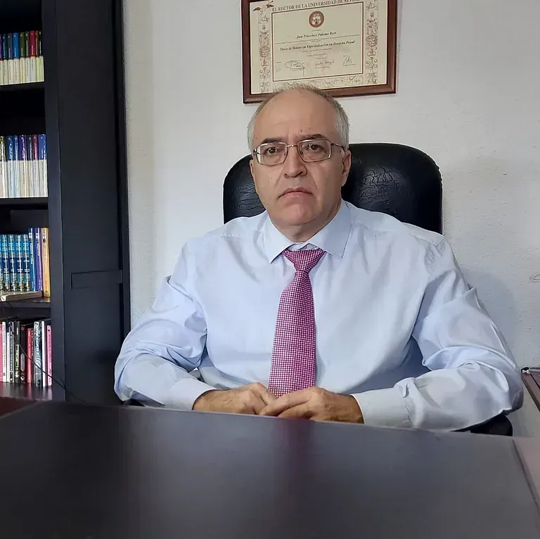 Un hombre con gafas y corbata está sentado en un escritorio.