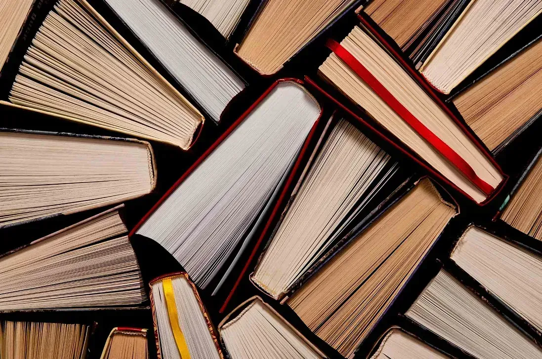 Un montón de libros están apilados uno encima del otro sobre una mesa.