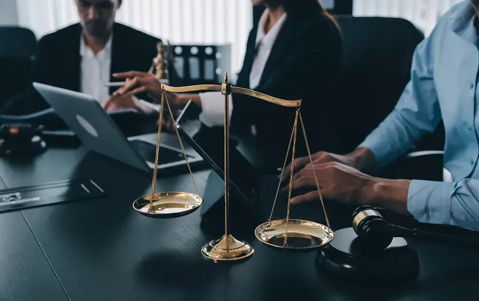 Un grupo de abogados está sentado en una mesa con una balanza de justicia y un mazo.