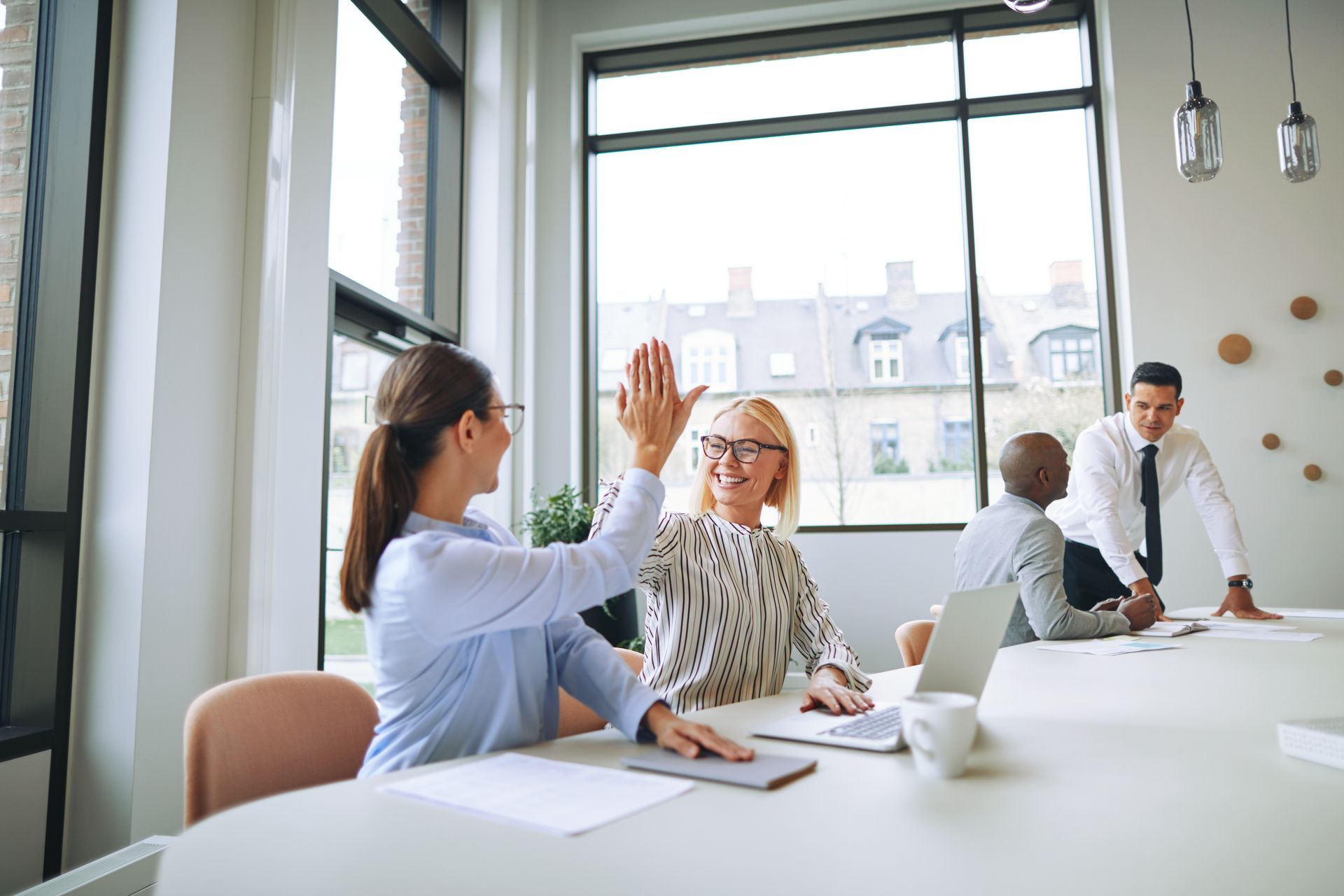 Eine Gruppe von Geschäftsleuten gibt sich in einem Konferenzraum gegenseitig ein High Five.