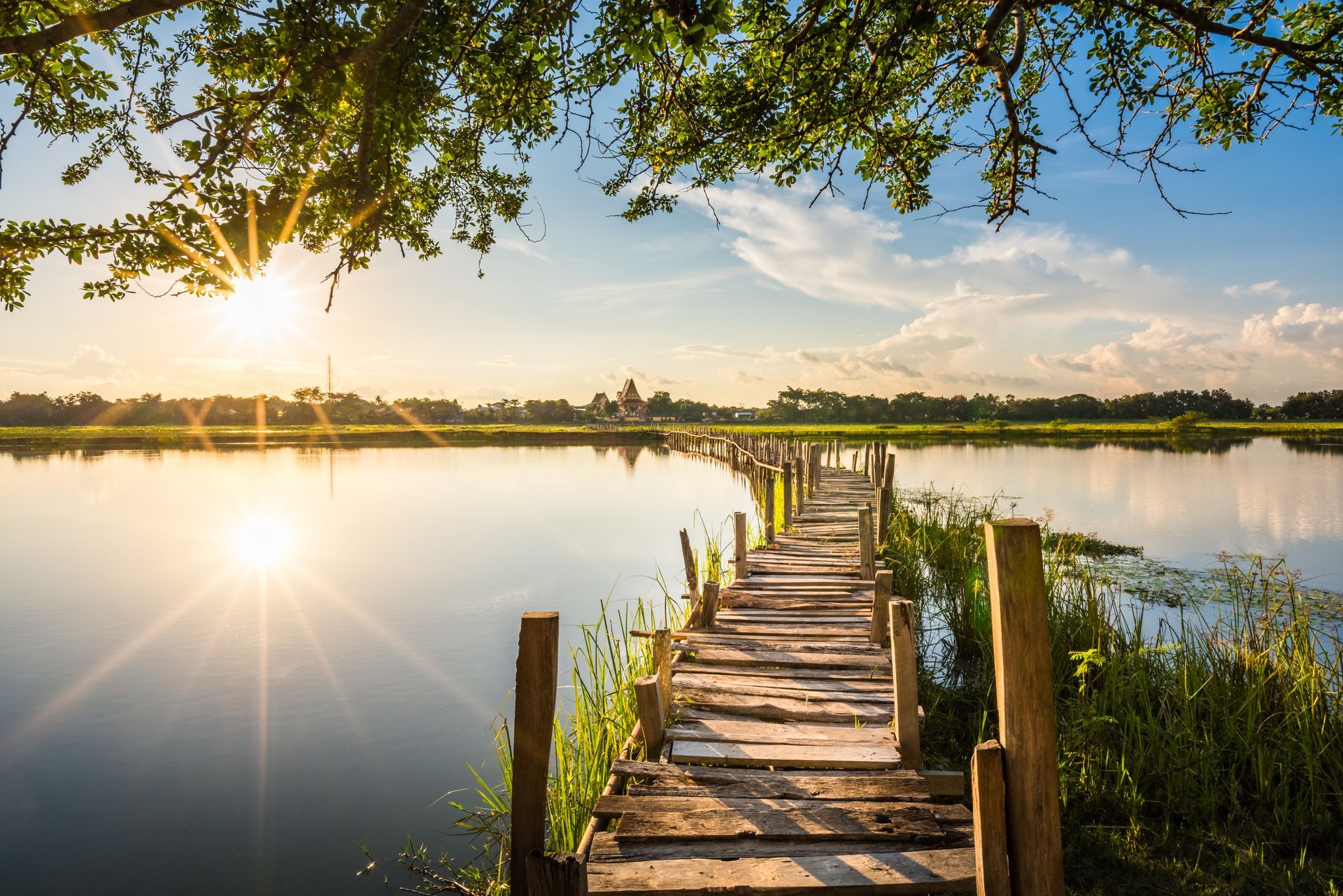 Eine Holzbrücke, die bei Sonnenuntergang zu einem See führt.