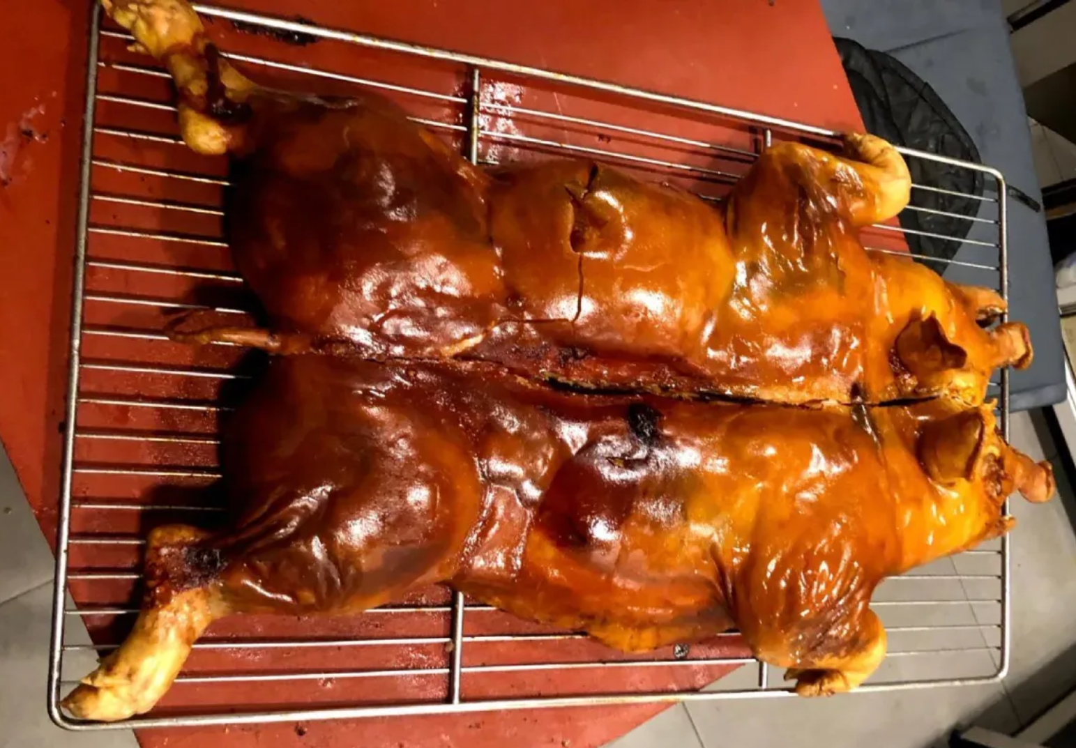 Dos pollos enteros asados ​​sobre una rejilla metálica, glaseados hasta obtener un color dorado y partidos por la mitad.