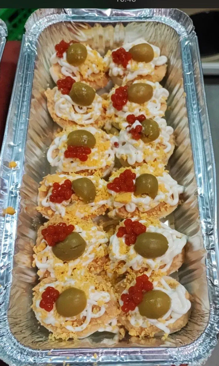 Bandeja de panecillos pequeños rellenos de queso, tomates cherry y aceitunas verdes.