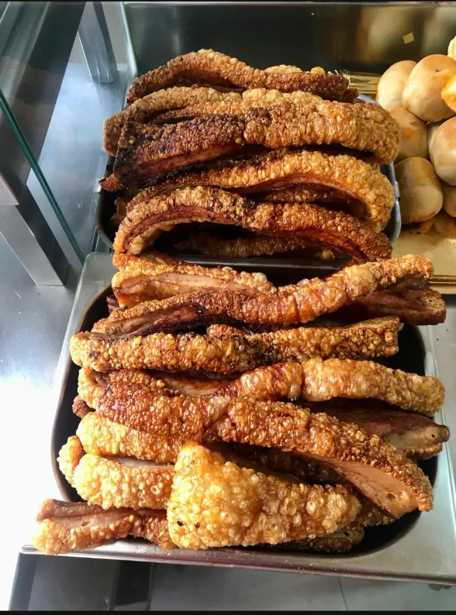 Pasteles fritos cubiertos de sésamo apilados en una vitrina.