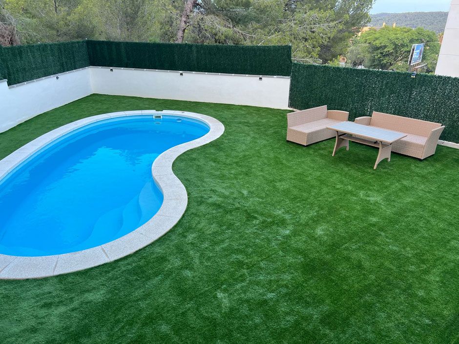 Una gran piscina está rodeada de un exuberante césped verde.