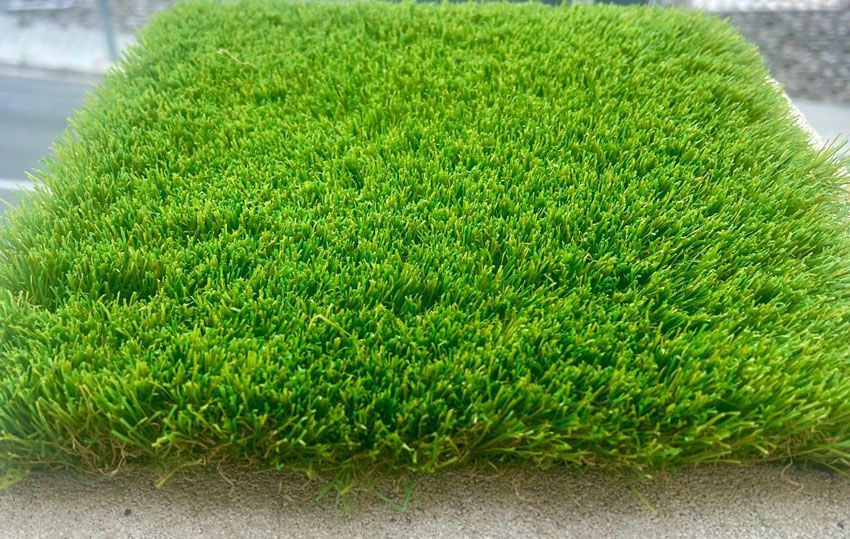 Un trozo de césped verde reposa sobre una superficie de hormigón.