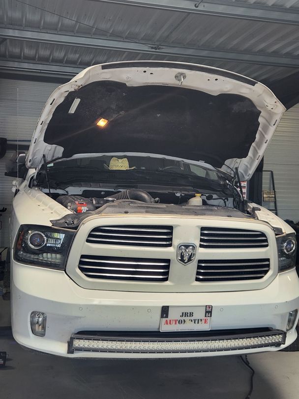 Camionnette Dodge Ram blanche, capot ouvert, dans un garage, vue de face.